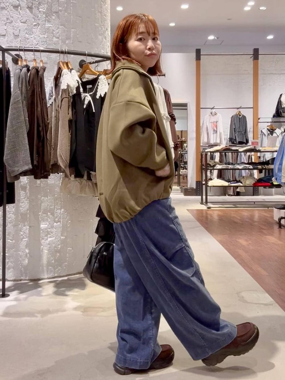 ブラウン系のローファー、ブルー系のその他パンツ、ブラック系のボストンバッグを着用したレディースの秋コーディネートの3枚目の写真