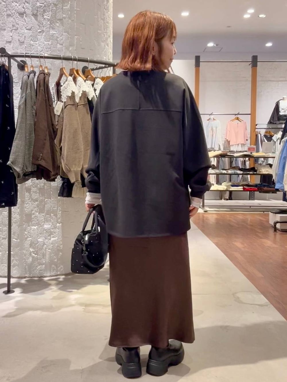 ブラウン系のスカート、ブラック系のブーツ、グリーン系のTシャツ/カットソーを着用したレディースの秋コーディネートの4枚目の写真