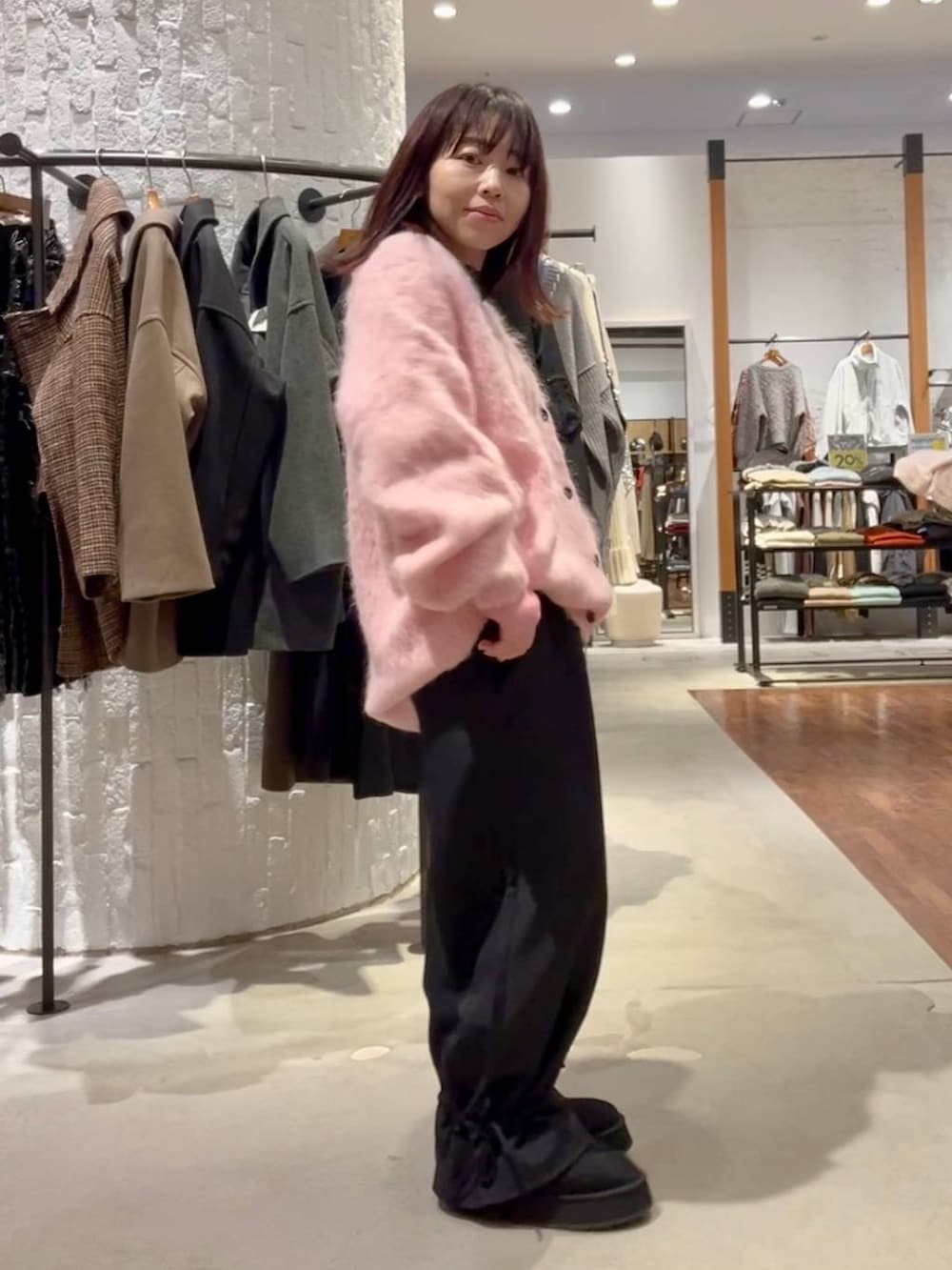 グレー系のニット/セーター、ブラック系のその他パンツ、ピンク系のカーディガン/ボレロを着用したレディースの秋コーディネートの3枚目の写真