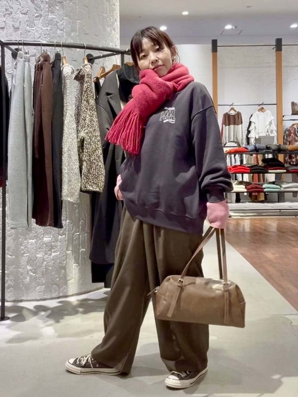 グレー系のニット/セーター、ブラウン系のスニーカー、ブラウン系のボストンバッグを着用したレディースの冬コーディネートの2枚目の写真