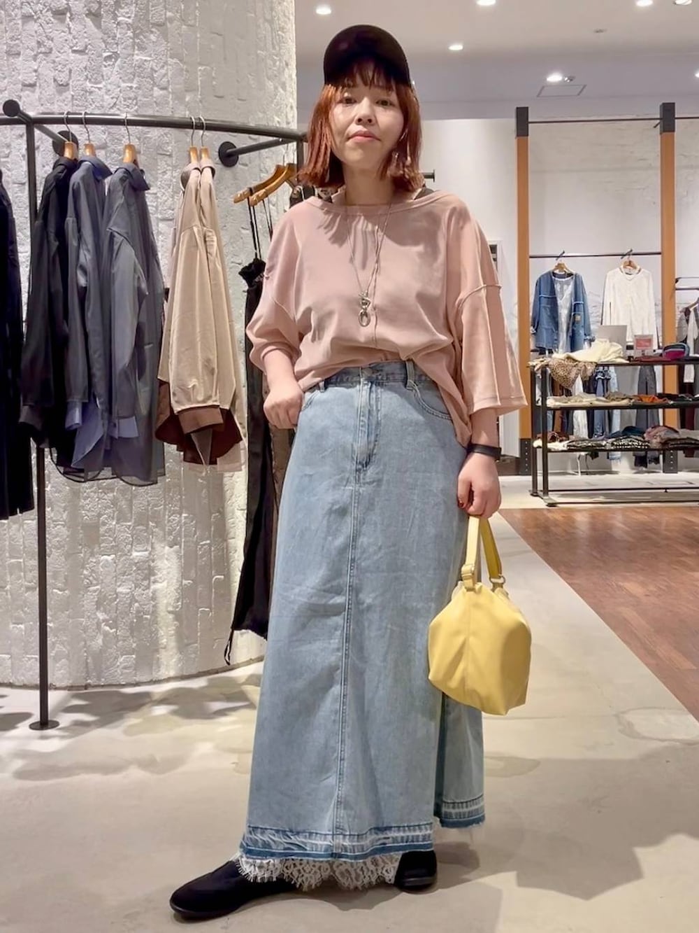 ブルー系のデニムスカート、イエロー系のショルダーバッグ、ブラック系のパンプスを着用したレディースの秋コーディネートの2枚目の写真
