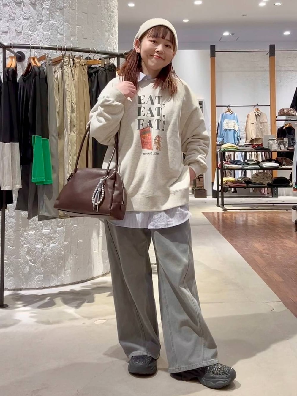 ブラック系のブーツ、グレー系のデニムパンツ、ブラウン系のボストンバッグを着用したレディースの春コーディネートの2枚目の写真