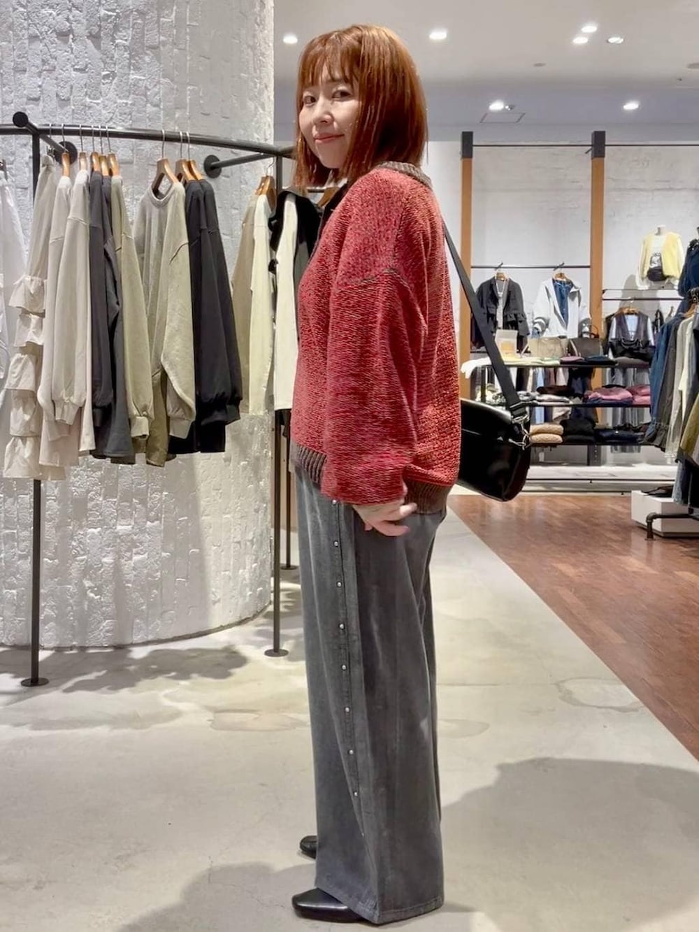 ブラック系のTシャツ/カットソー、グレー系のデニムパンツ、レッド系のニット/セーターを着用したレディースの秋コーディネートの3枚目の写真