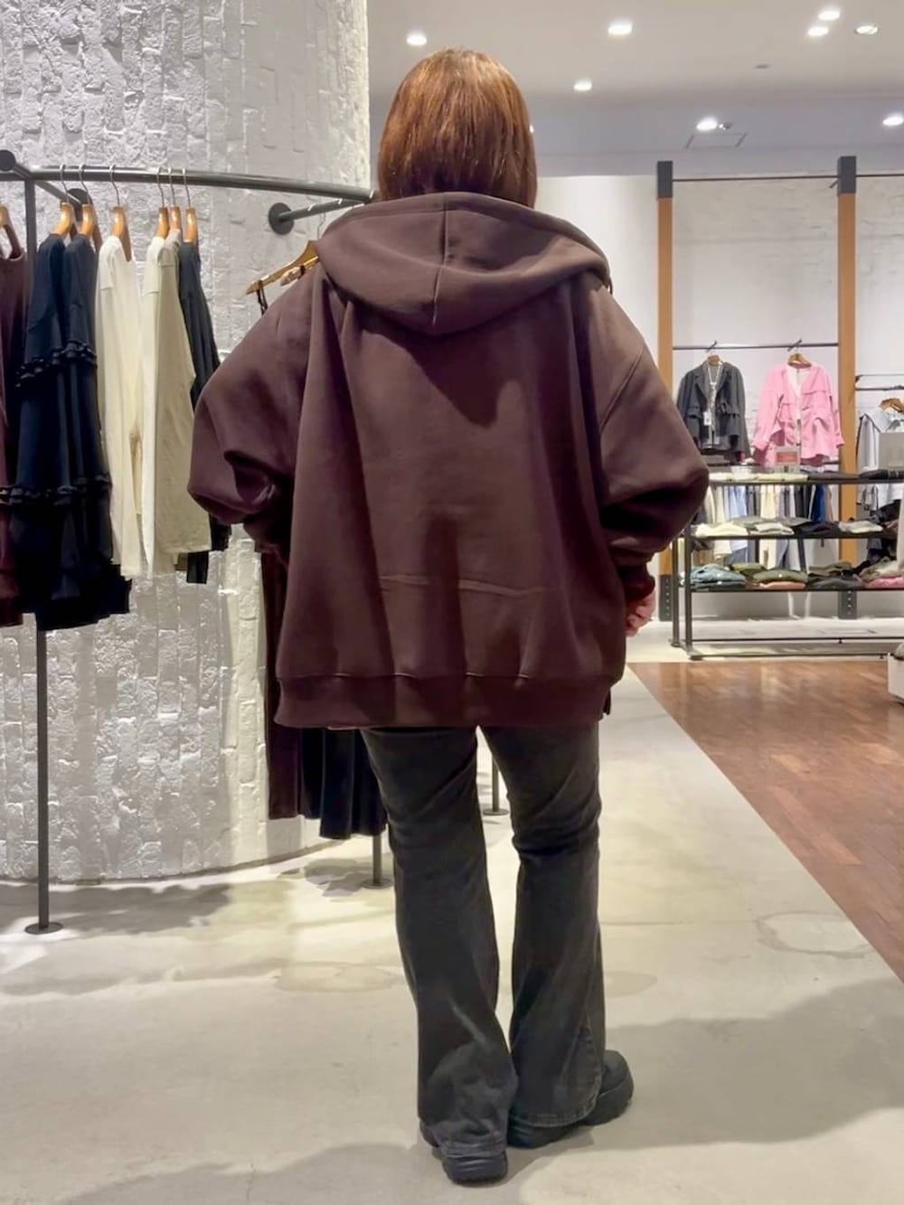 ブラック系のスニーカー、ブラウン系のパーカー、グレー系のデニムパンツを着用したレディースの秋コーディネートの5枚目の写真