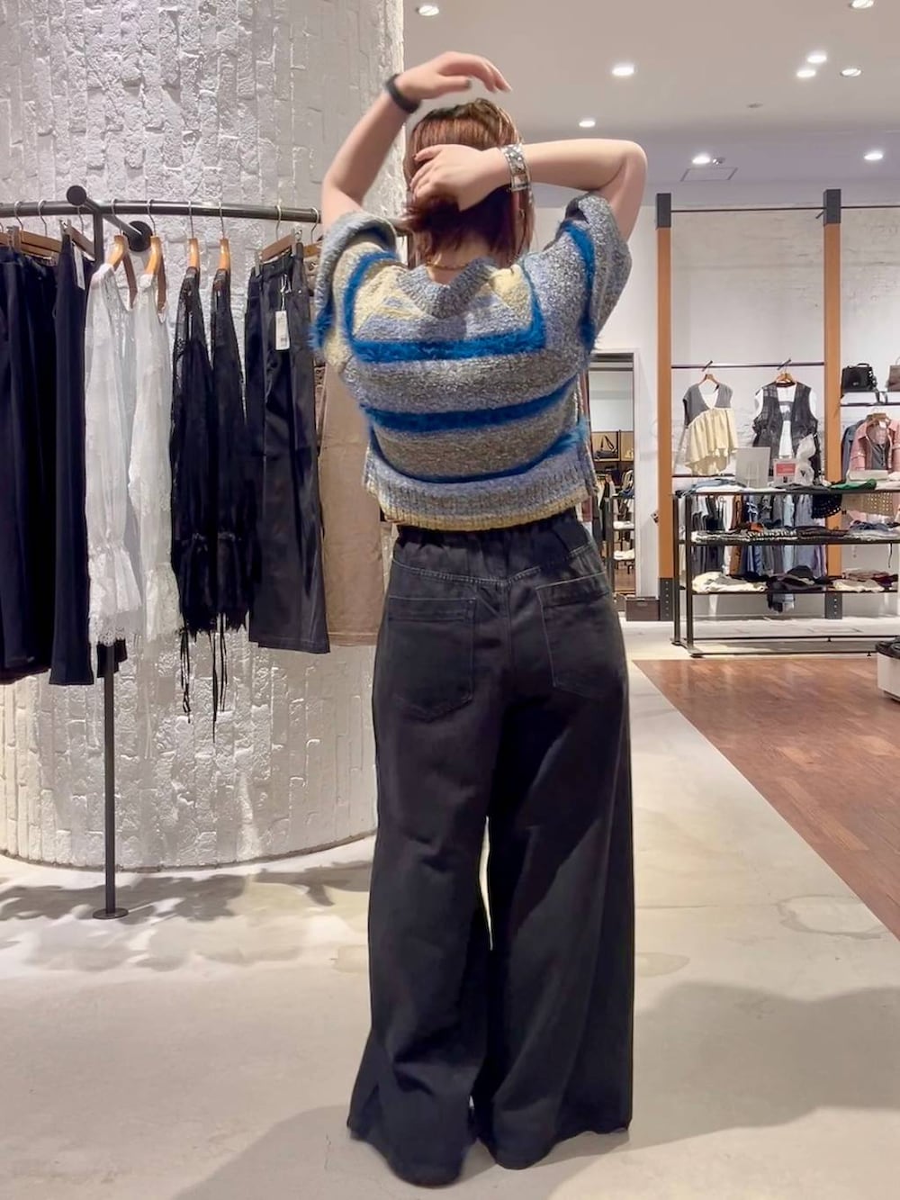 ブラック系のパンプス、ブルー系のニット/セーター、ブラック系のデニムパンツを着用したレディースの夏コーディネートの4枚目の写真