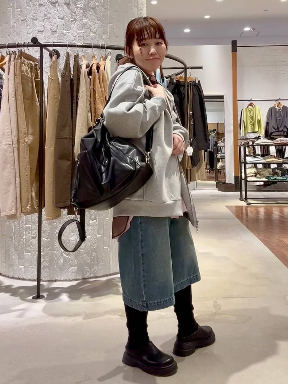 グレー系のパーカー、ブラック系のショルダーバッグ、ブラック系のその他シューズを着用したレディースの冬コーディネートの2枚目の写真