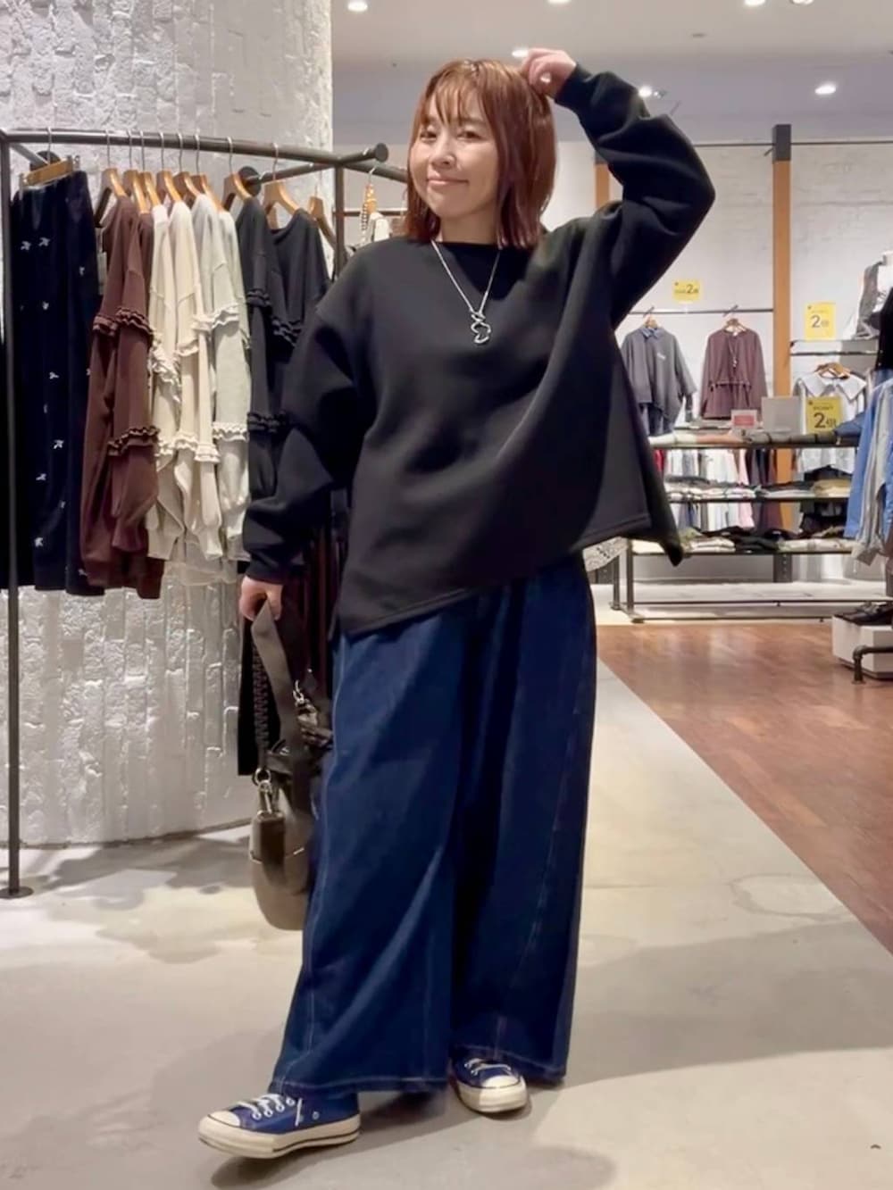 ブルー系のスニーカー、グリーン系のショルダーバッグ、ブルー系のデニムパンツを着用したレディースの秋コーディネートの2枚目の写真