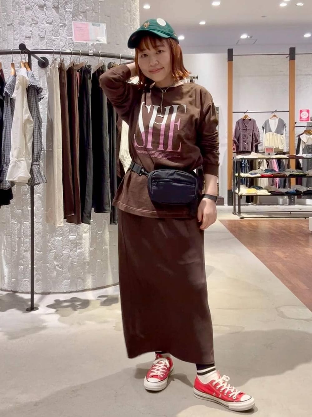ブラウン系のスカート、ブラウン系のTシャツ/カットソー、レッド系のスニーカーを着用したレディースの秋コーディネートの2枚目の写真