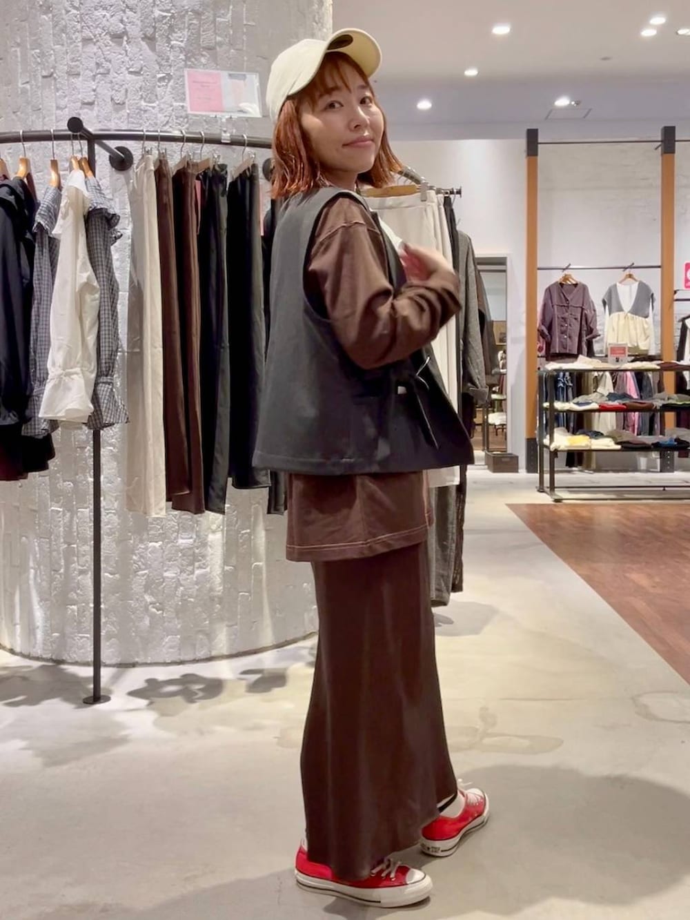 ブラウン系のスカート、ブラウン系のTシャツ/カットソー、レッド系のスニーカーを着用したレディースの秋コーディネートの3枚目の写真