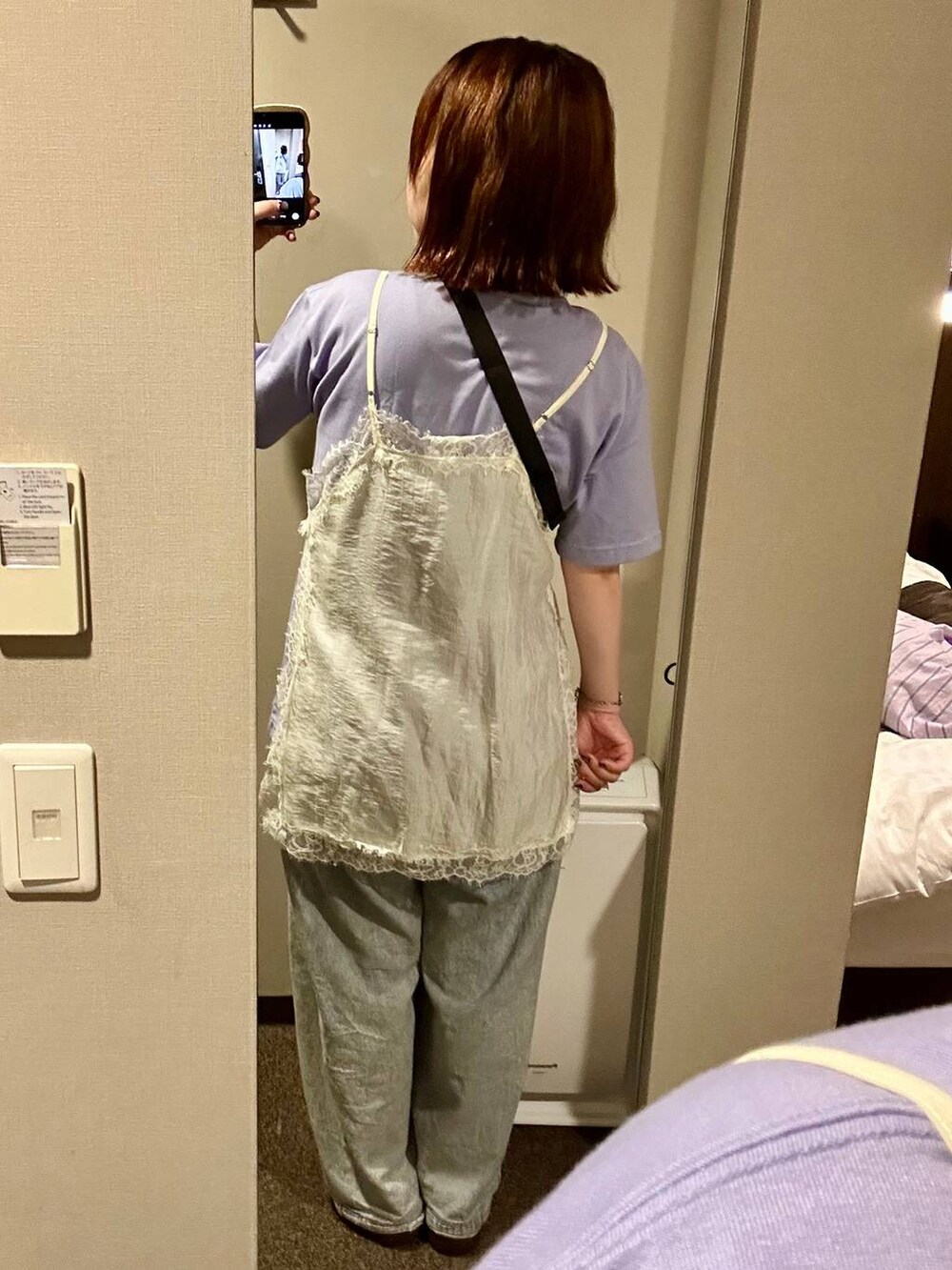 パープル系のトートバッグ、ブラック系のスニーカー、ブルー系のデニムパンツを着用したレディースの夏コーディネートの4枚目の写真