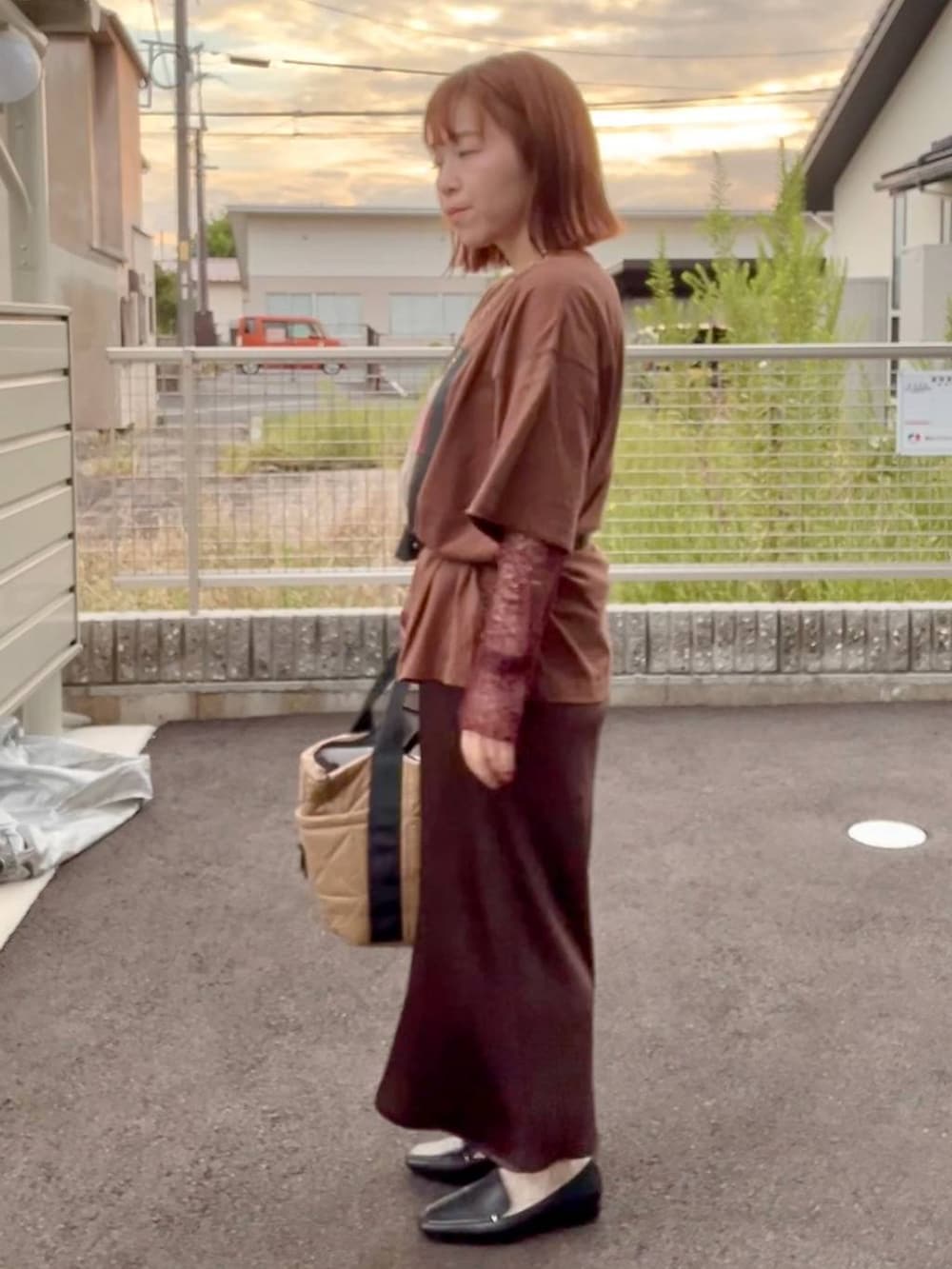 ブラウン系のスカート、ブラウン系のTシャツ/カットソー、ゴールド系のネックレスを着用したレディースの秋コーディネートの3枚目の写真