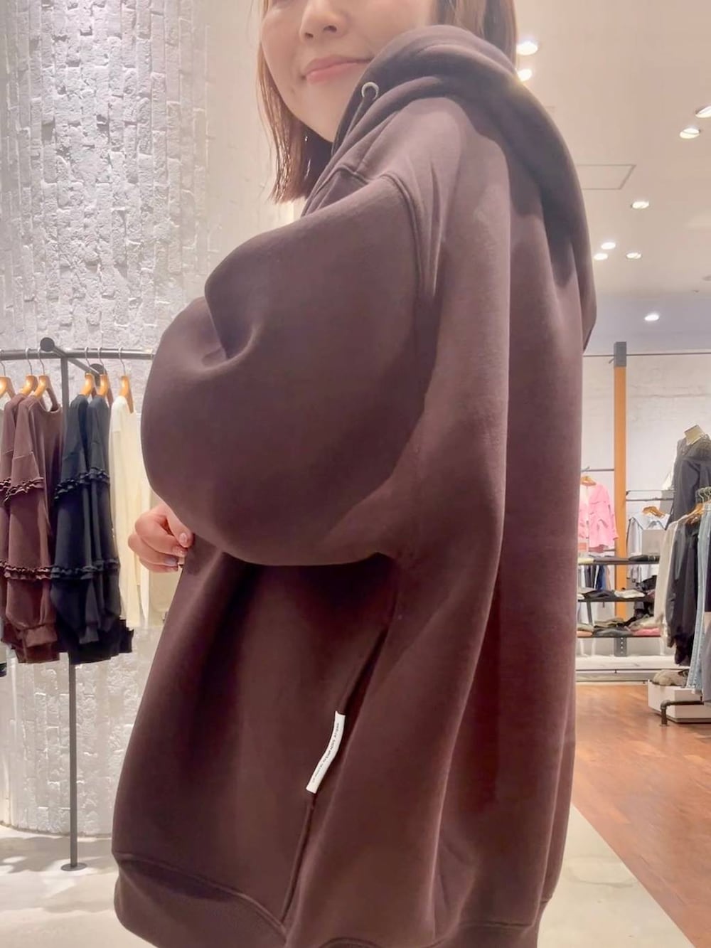 ブラック系のスニーカー、ブラウン系のパーカー、グレー系のデニムパンツを着用したレディースの秋コーディネートの6枚目の写真