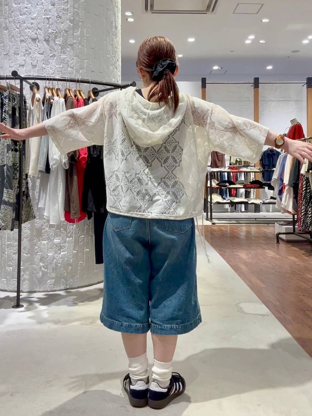 ブラック系のスニーカー、ブラウン系のショルダーバッグ、ブルー系のデニムパンツを着用したレディースの春コーディネートの6枚目の写真