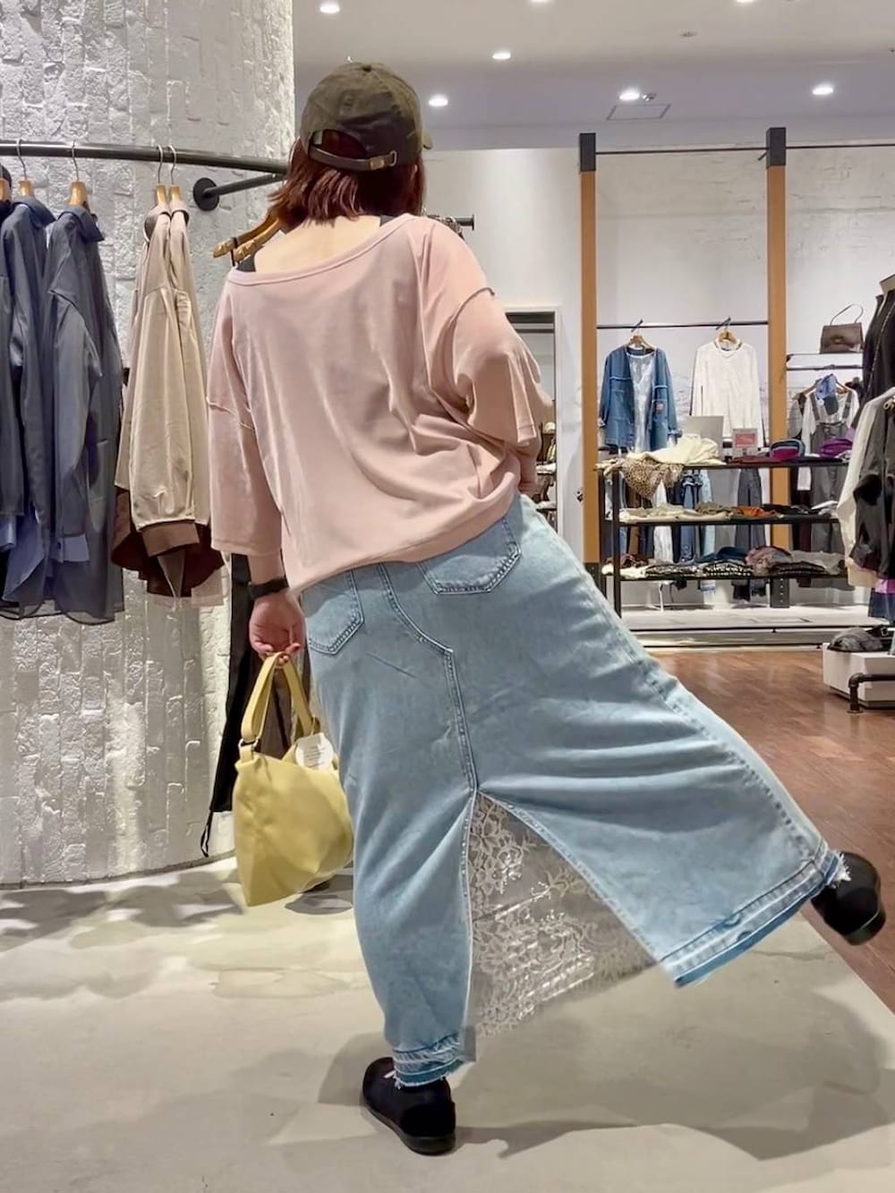 ブルー系のデニムスカート、イエロー系のショルダーバッグ、ブラック系のパンプスを着用したレディースの秋コーディネートの4枚目の写真