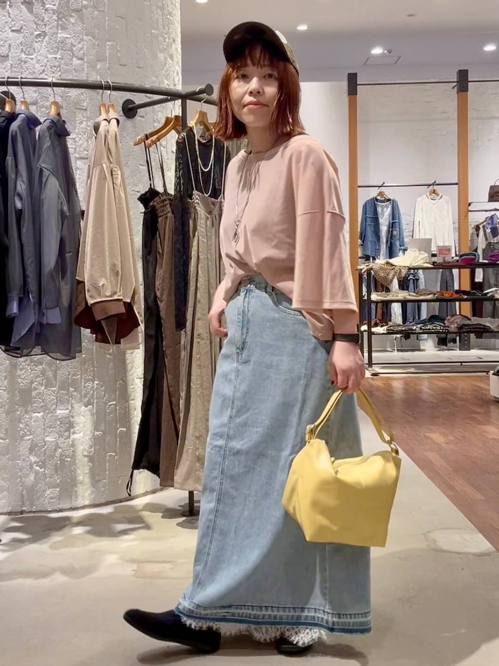 ブルー系のデニムスカート、イエロー系のショルダーバッグ、ブラック系のパンプスを着用したレディースの秋コーディネートの3枚目の写真