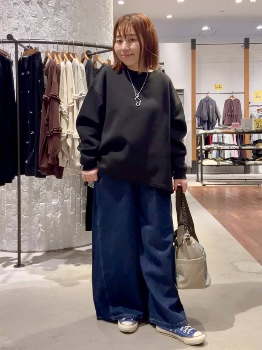 ブルー系のスニーカー、グリーン系のショルダーバッグ、ブルー系のデニムパンツを着用したレディースの秋コーディネートの5枚目の写真