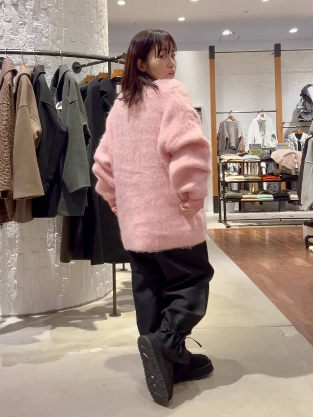 グレー系のニット/セーター、ブラック系のその他パンツ、ピンク系のカーディガン/ボレロを着用したレディースの秋コーディネートの4枚目の写真