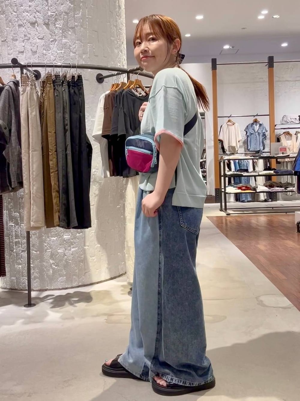 ブルー系のニット/セーター、ブルー系のデニムパンツ、ブラック系のサンダルを着用したレディースの夏コーディネートの3枚目の写真