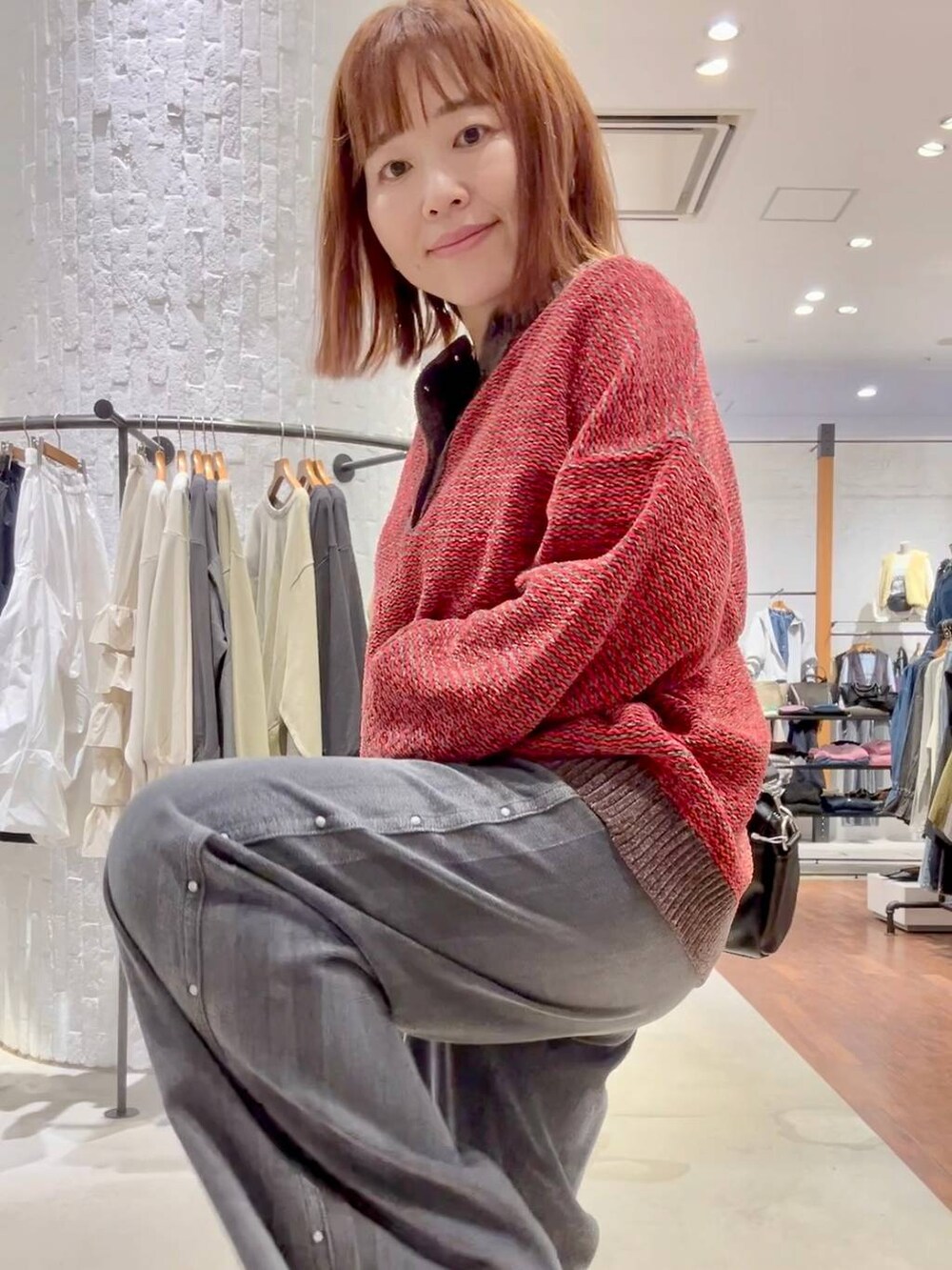 ブラック系のTシャツ/カットソー、グレー系のデニムパンツ、レッド系のニット/セーターを着用したレディースの秋コーディネートの6枚目の写真