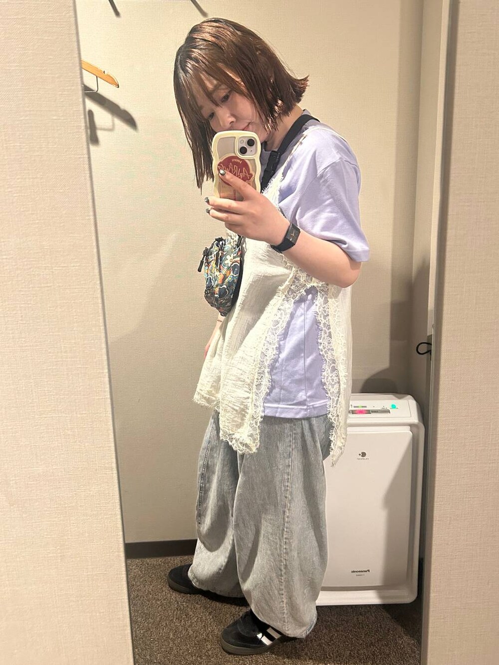 パープル系のトートバッグ、ブラック系のスニーカー、ブルー系のデニムパンツを着用したレディースの夏コーディネートの6枚目の写真
