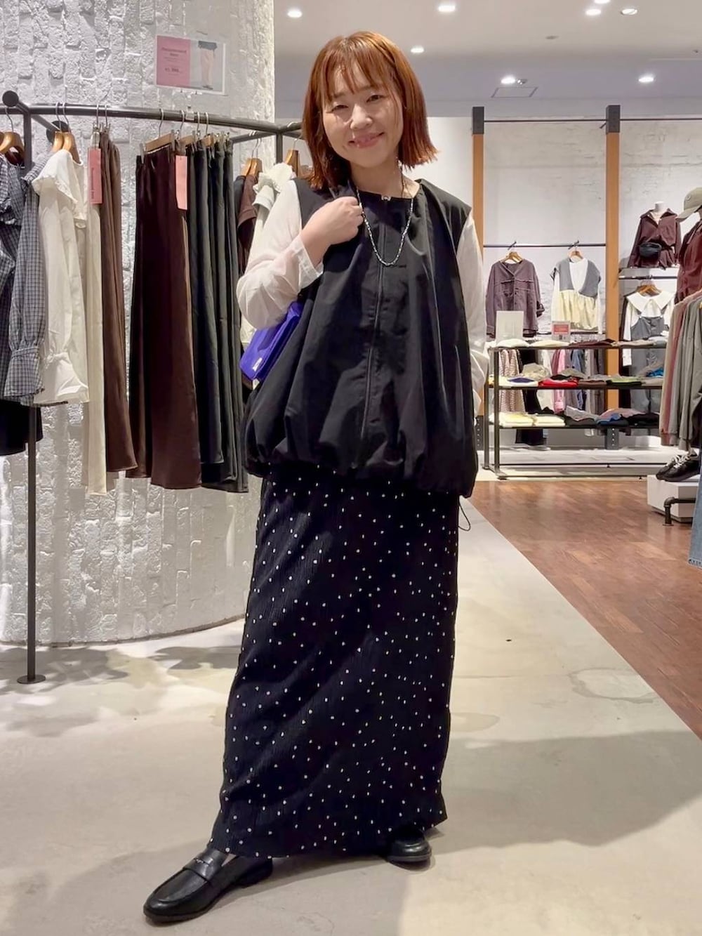 ブラック系のベスト、ブラック系のローファー、ホワイト系のTシャツ/カットソーを着用したレディースの秋コーディネートの2枚目の写真
