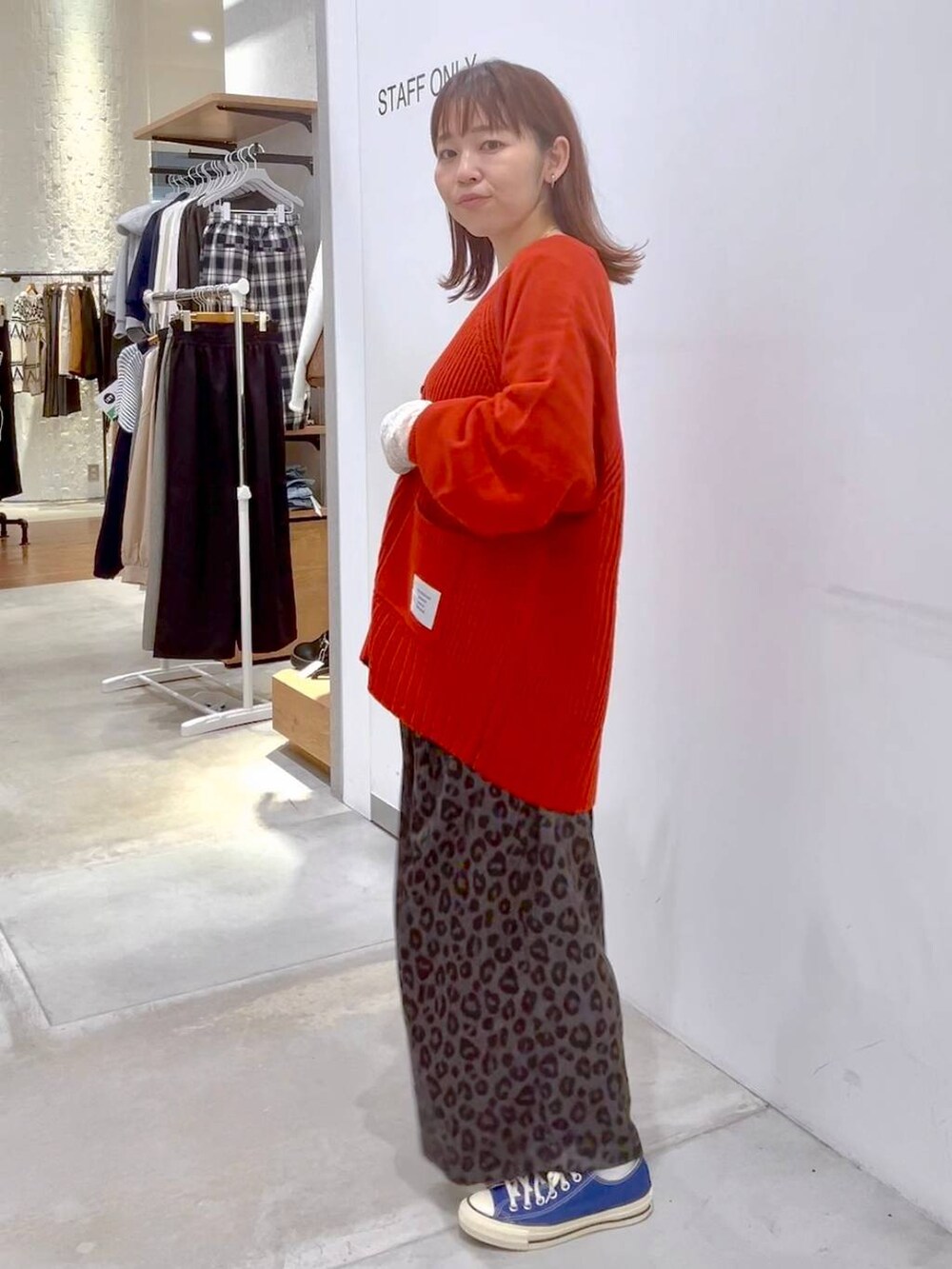 ホワイト系のTシャツ/カットソー、レッド系のカーディガン/ボレロ、ブルー系のスニーカーを着用したレディースの秋コーディネートの3枚目の写真