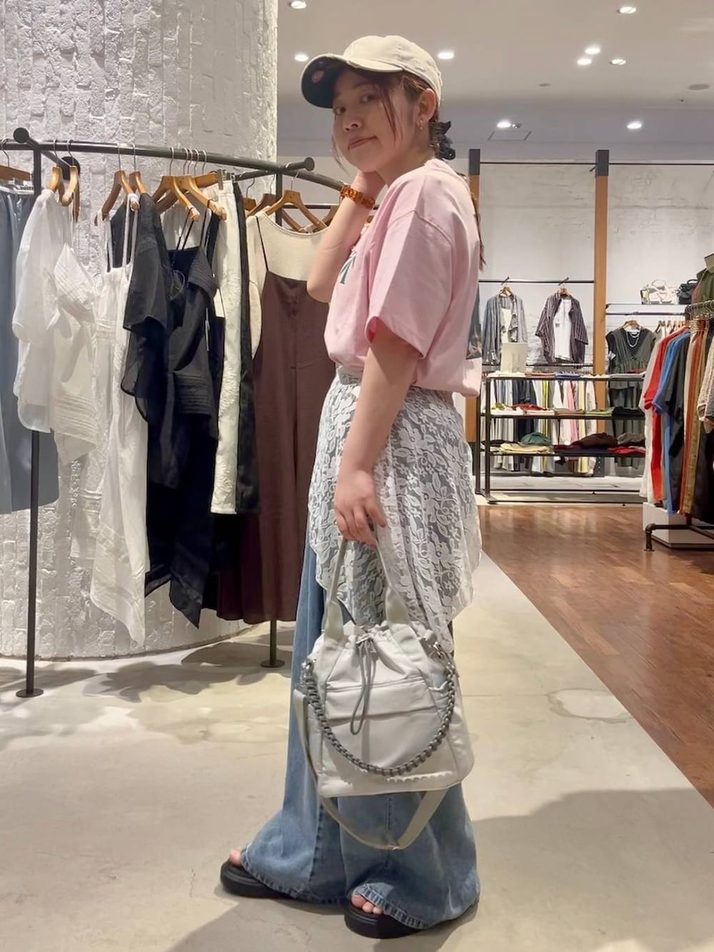 ブルー系のデニムパンツ、グレー系のショルダーバッグ、その他のサンダルを着用したレディースの夏コーディネートの3枚目の写真