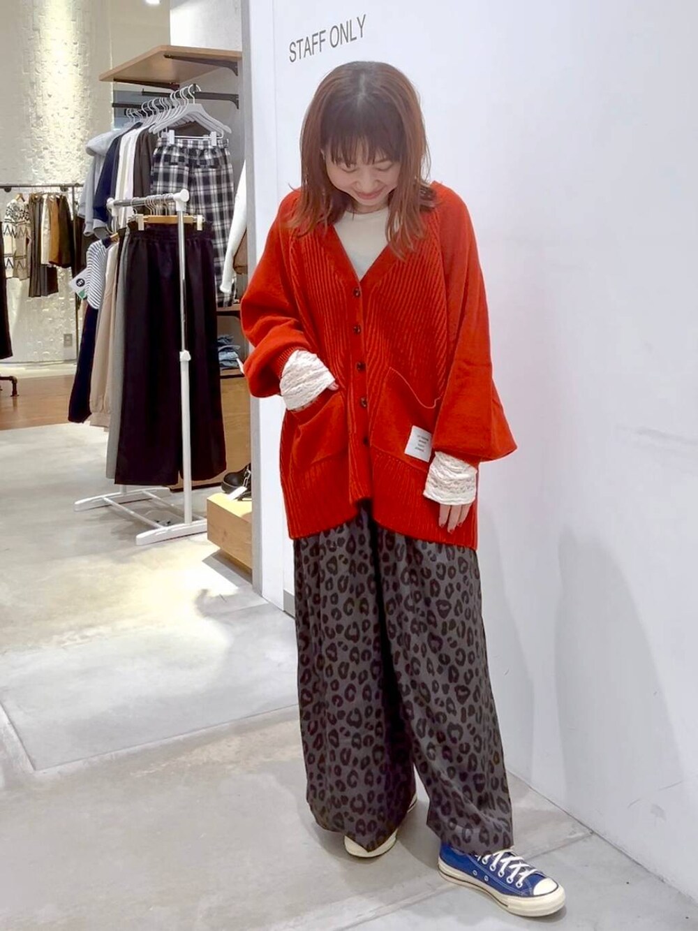 ホワイト系のTシャツ/カットソー、レッド系のカーディガン/ボレロ、ブルー系のスニーカーを着用したレディースの秋コーディネートの2枚目の写真