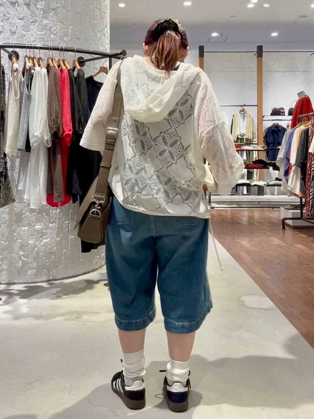 ブラック系のスニーカー、ブラウン系のショルダーバッグ、ブルー系のデニムパンツを着用したレディースの春コーディネートの5枚目の写真