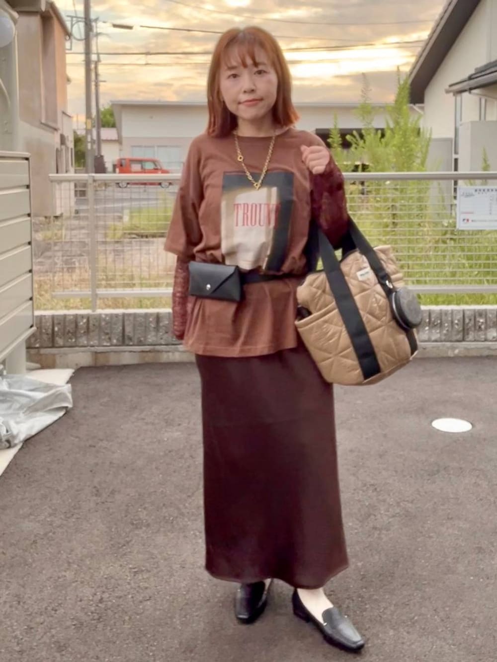 ブラウン系のスカート、ブラウン系のTシャツ/カットソー、ゴールド系のネックレスを着用したレディースの秋コーディネートの2枚目の写真