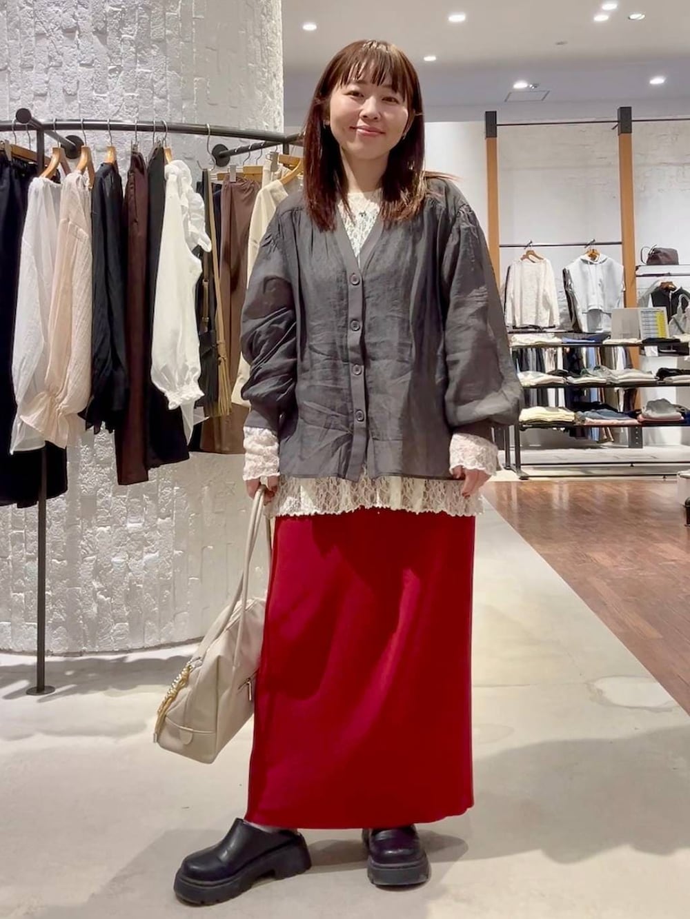 レッド系のスカート、ホワイト系のボストンバッグ、ブラック系のその他シューズを着用したレディースの春コーディネートの2枚目の写真