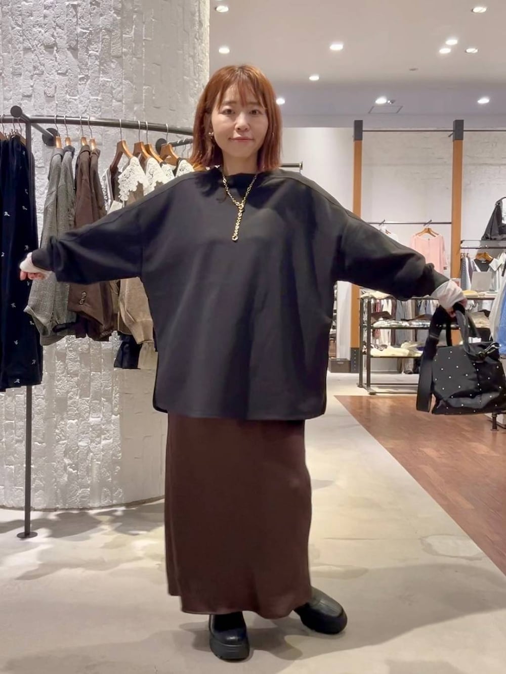 ブラウン系のスカート、ブラック系のブーツ、グリーン系のTシャツ/カットソーを着用したレディースの秋コーディネートの2枚目の写真