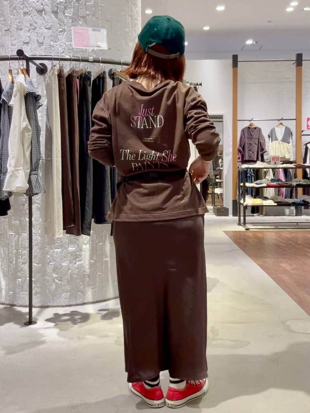 ブラウン系のスカート、ブラウン系のTシャツ/カットソー、レッド系のスニーカーを着用したレディースの秋コーディネートの4枚目の写真
