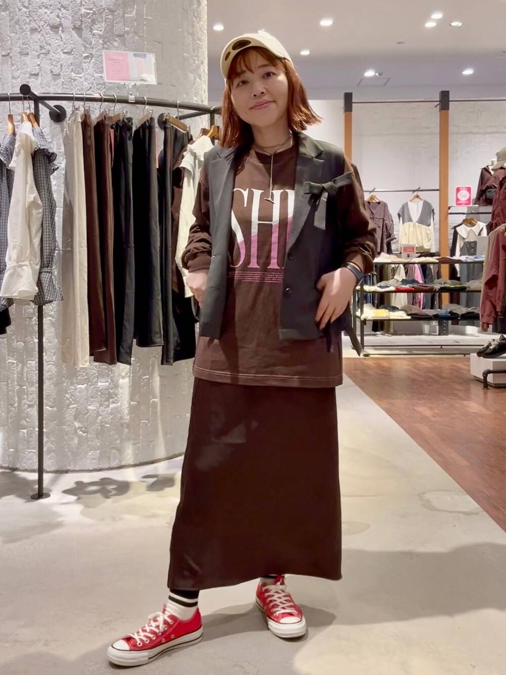 ブラウン系のスカート、ブラウン系のTシャツ/カットソー、レッド系のスニーカーを着用したレディースの秋コーディネートの2枚目の写真