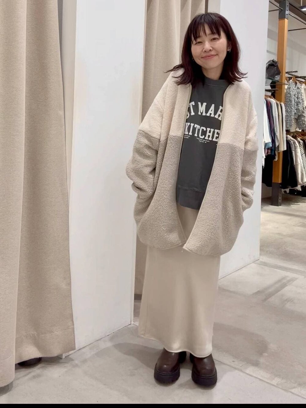 ホワイト系のスカート、ホワイト系のその他アウター、ブラウン系のブーツを着用したレディースの秋コーディネートの2枚目の写真