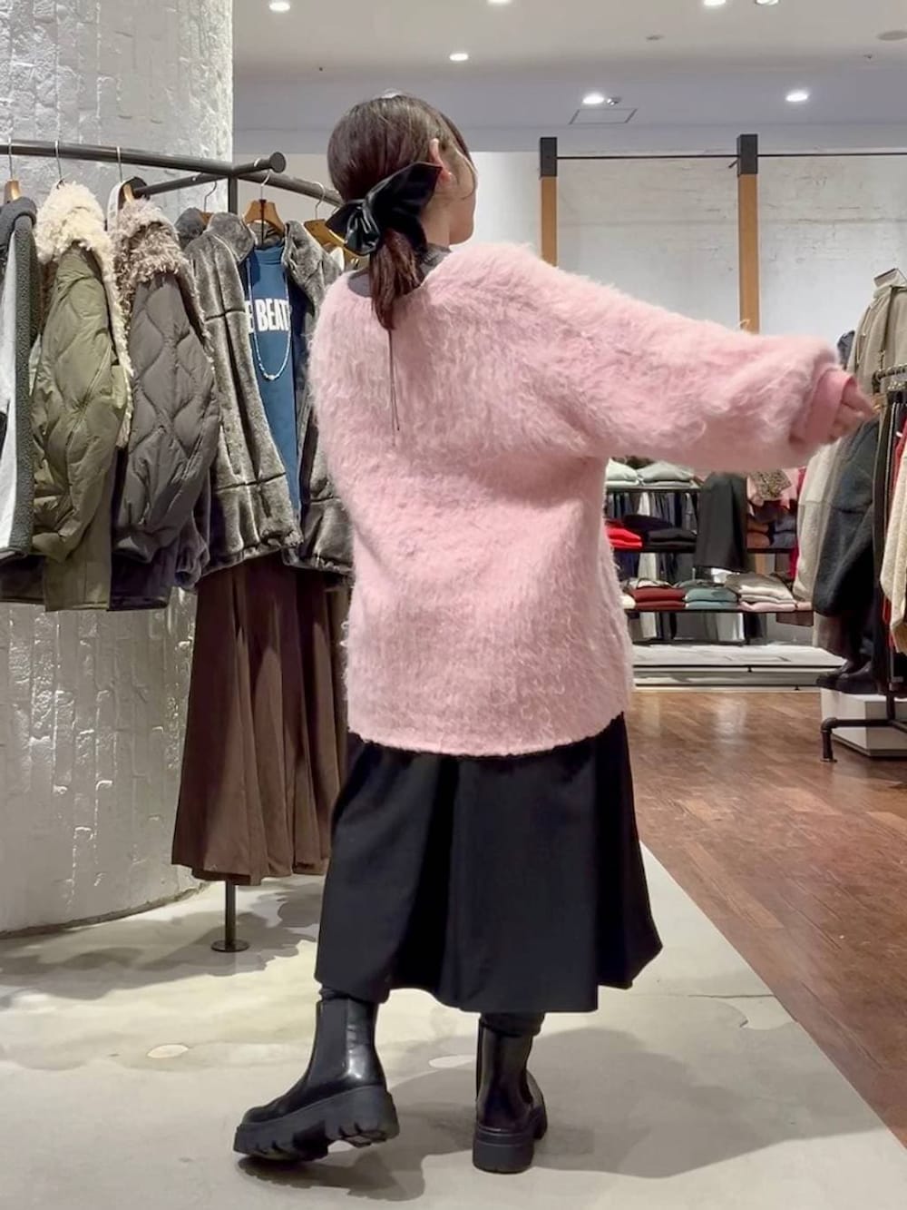 グレー系のニット/セーター、ブラック系のブーツ、ピンク系のカーディガン/ボレロを着用したレディースの冬コーディネートの4枚目の写真