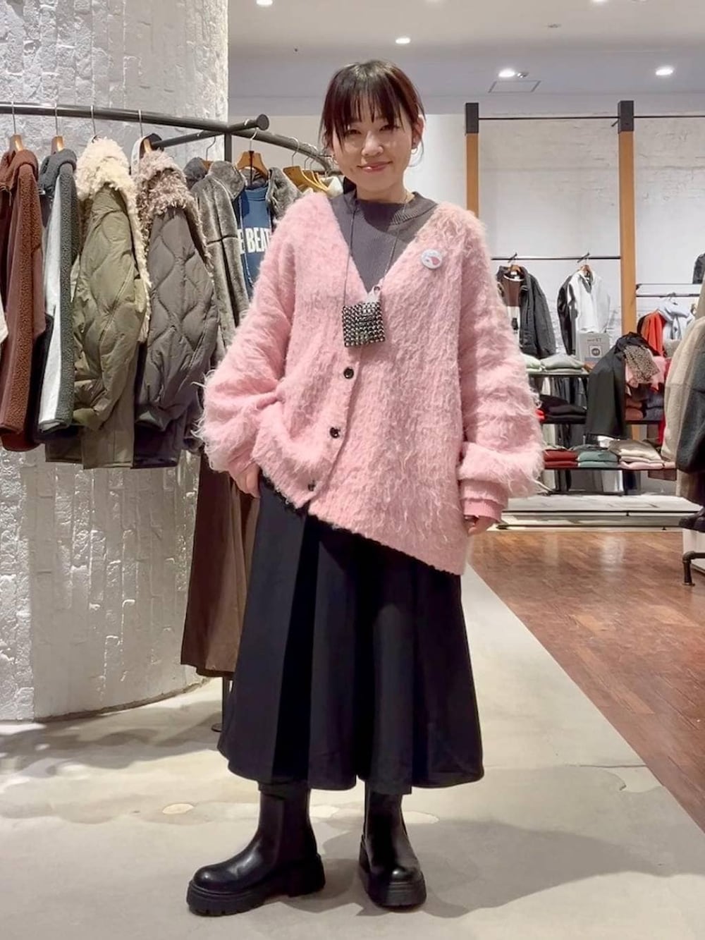 グレー系のニット/セーター、ブラック系のブーツ、ピンク系のカーディガン/ボレロを着用したレディースの冬コーディネートの2枚目の写真