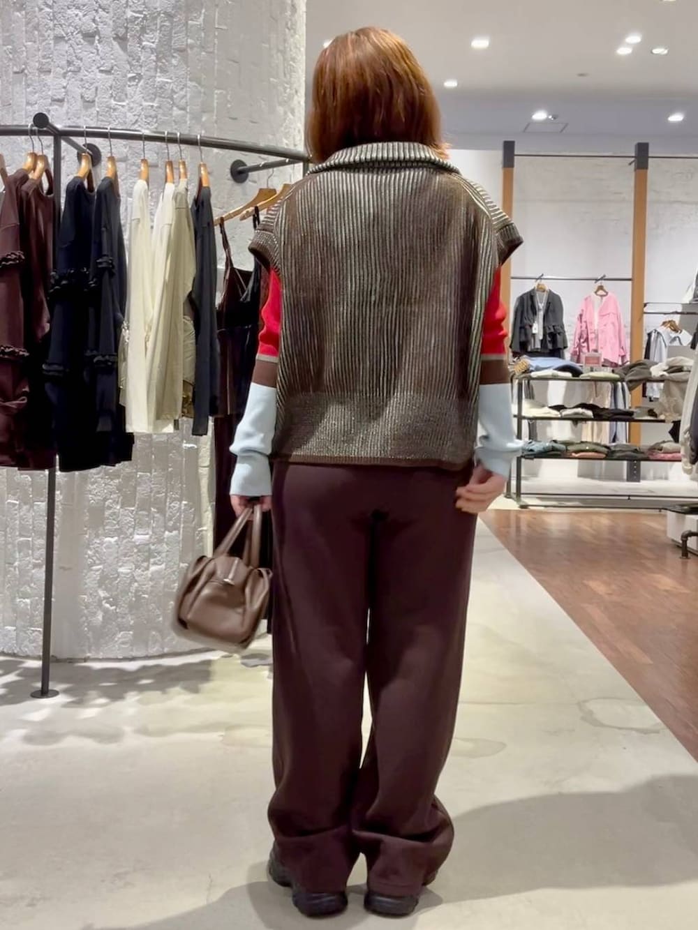レッド系のニット/セーター、ブラウン系のショルダーバッグ、ブラック系のスニーカーを着用したレディースの秋コーディネートの4枚目の写真