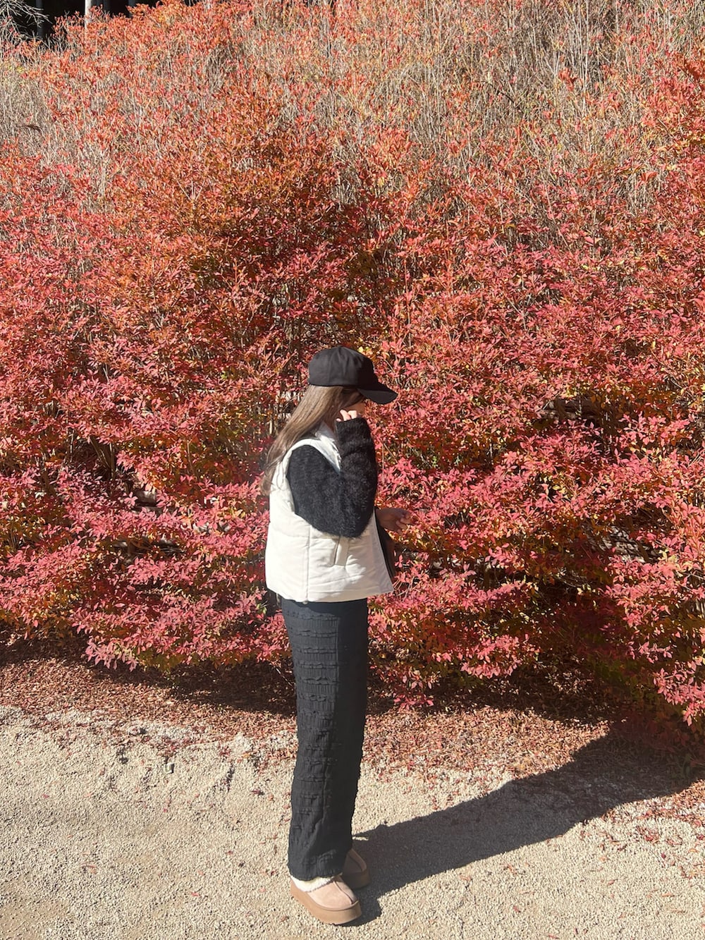 ブラック系のスカート、ブラック系のシューズ、ホワイト系のダウンベストを着用したレディースの冬コーディネートの2枚目の写真