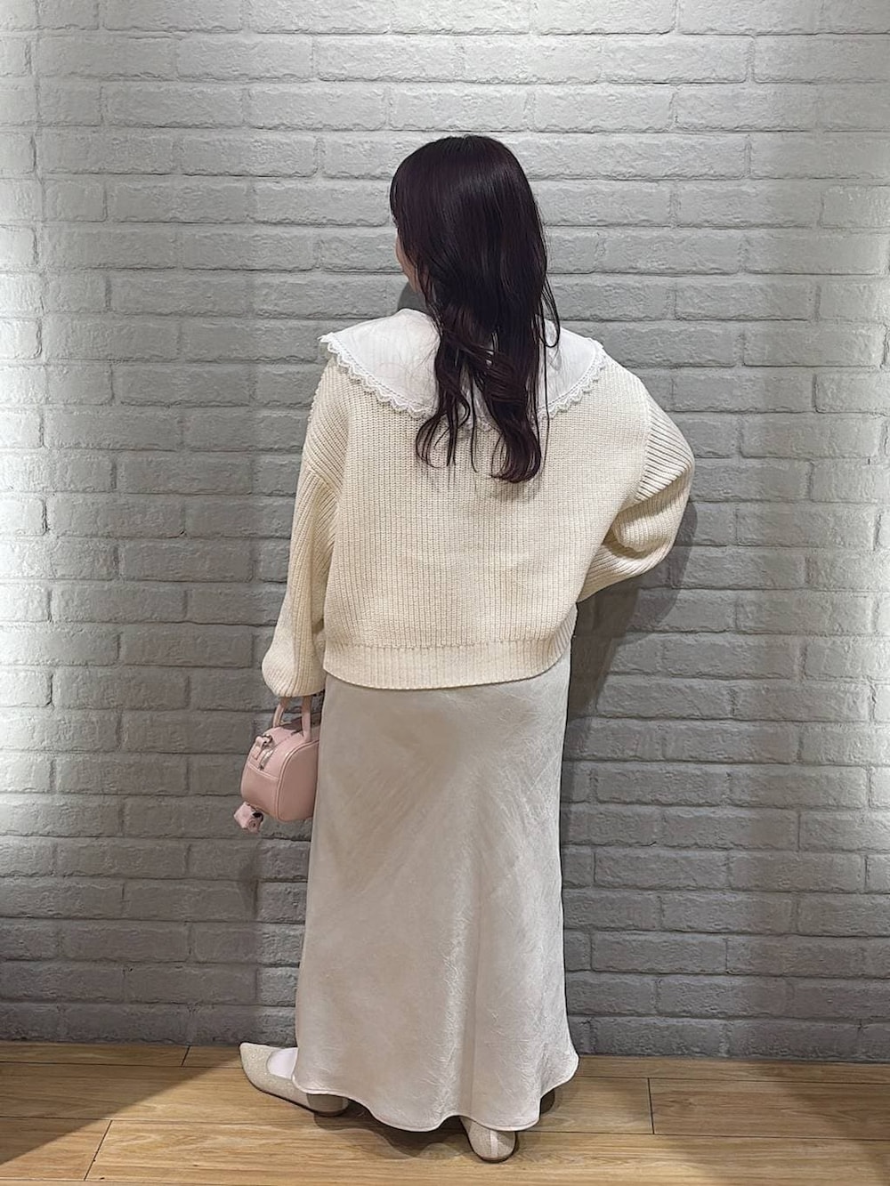 ホワイト系のスカート、ピンク系のボストンバッグ、ホワイト系のパンプスを着用したレディースの冬コーディネートの3枚目の写真