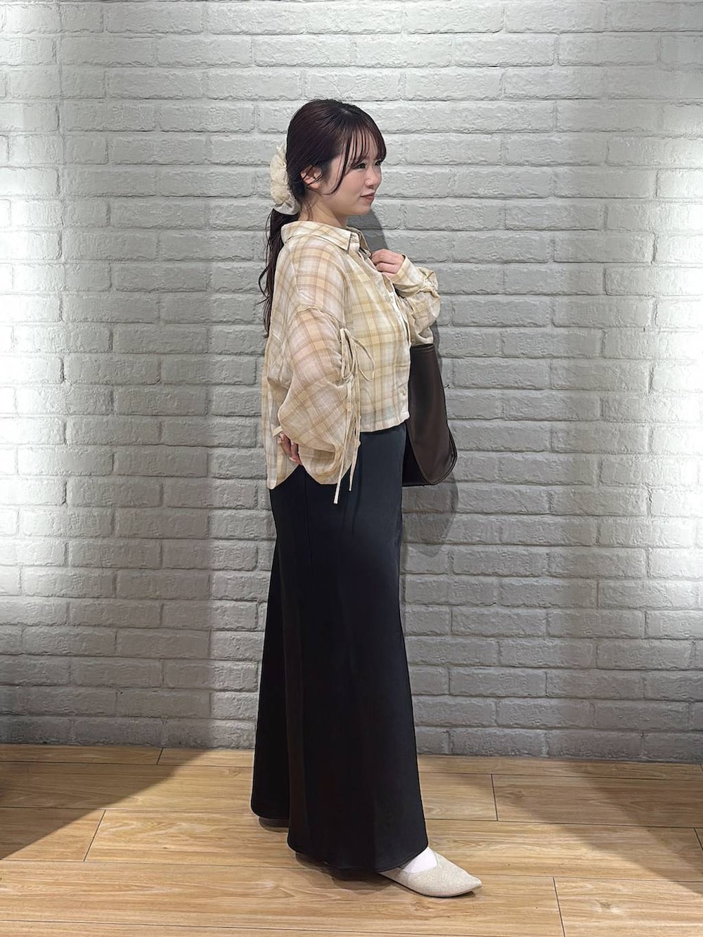 ブラック系のスカート、ホワイト系のパンプス、ブラウン系のトートバッグを着用したレディースの春コーディネートの4枚目の写真