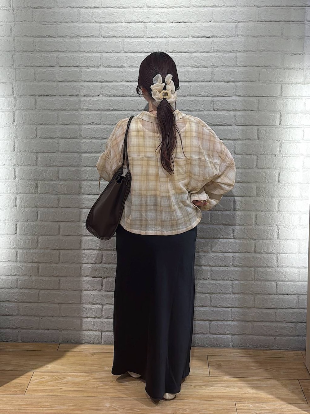 ブラック系のスカート、ホワイト系のパンプス、ブラウン系のトートバッグを着用したレディースの春コーディネートの3枚目の写真