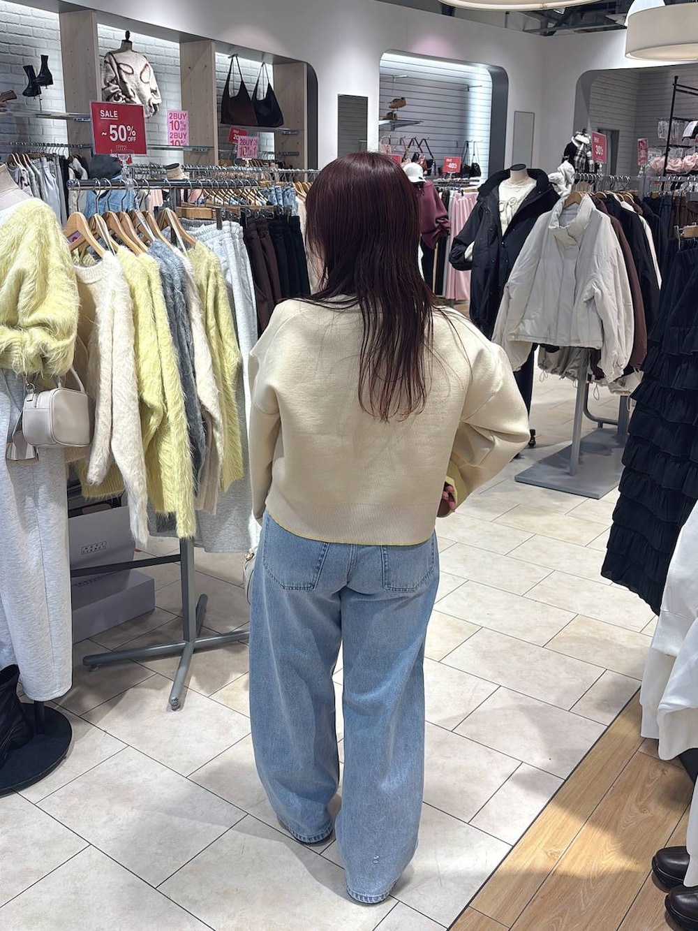 ホワイト系のボストンバッグ、ブルー系のデニムパンツ、ブラウン系のローファーを着用したレディースの冬コーディネートの3枚目の写真