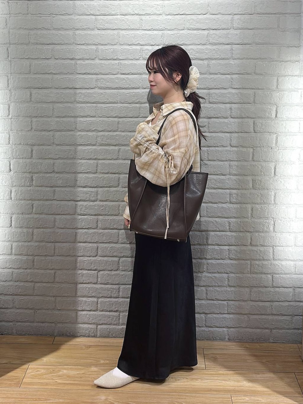 ブラック系のスカート、ホワイト系のパンプス、ブラウン系のトートバッグを着用したレディースの春コーディネートの2枚目の写真