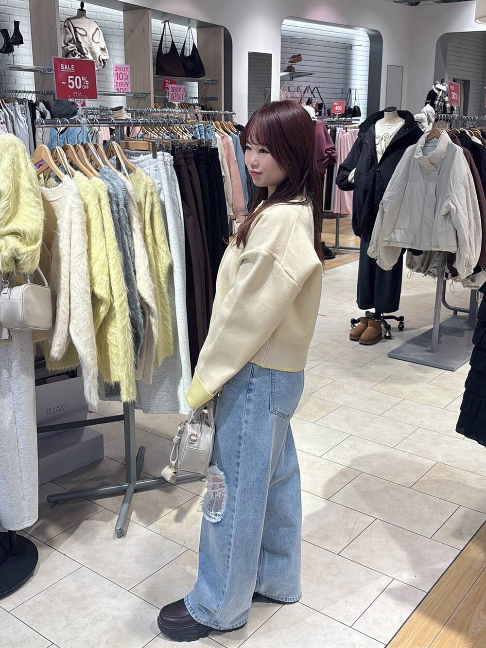 ホワイト系のボストンバッグ、ブルー系のデニムパンツ、ブラウン系のローファーを着用したレディースの冬コーディネートの2枚目の写真