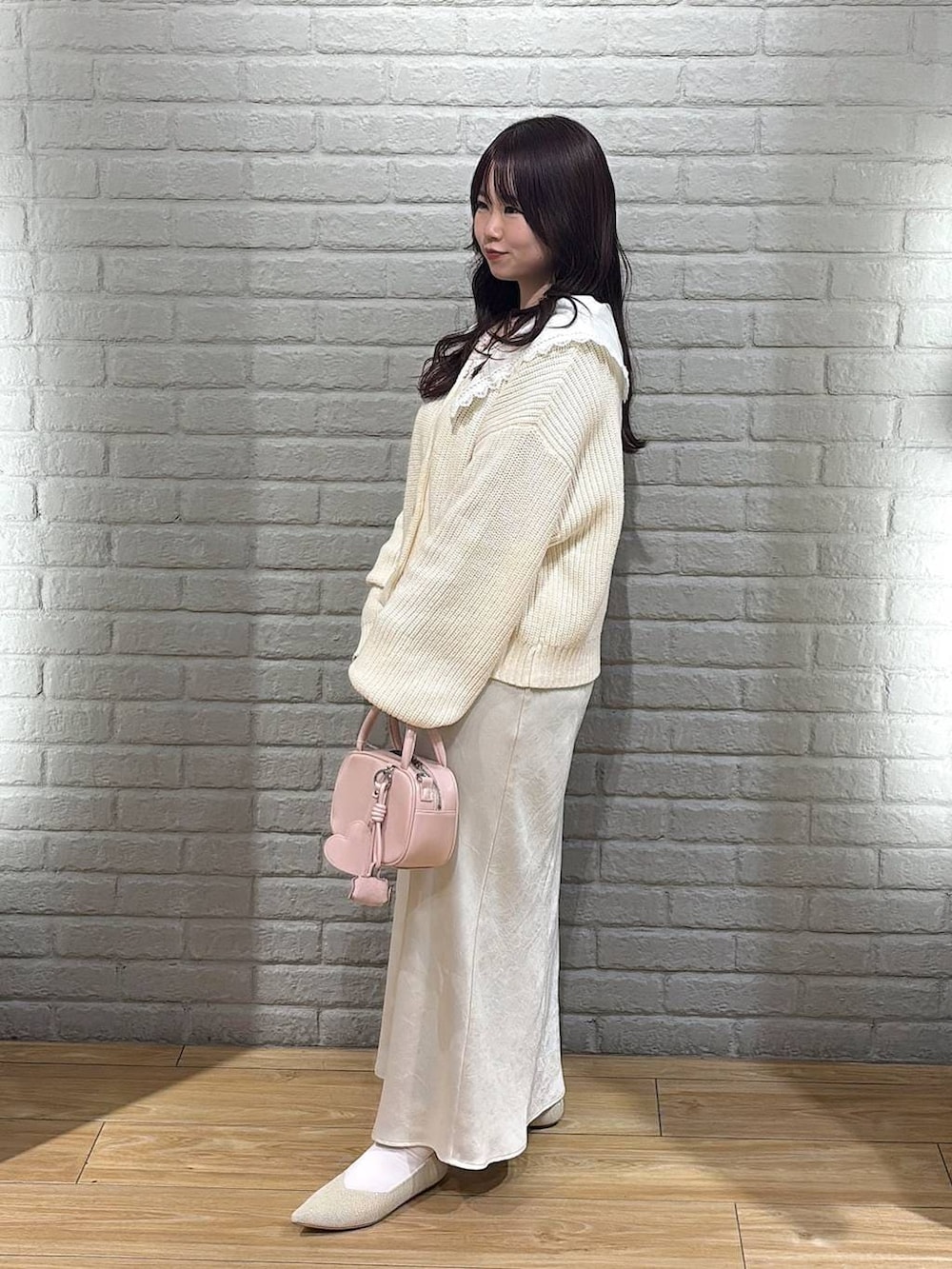 ホワイト系のスカート、ピンク系のボストンバッグ、ホワイト系のパンプスを着用したレディースの冬コーディネートの2枚目の写真