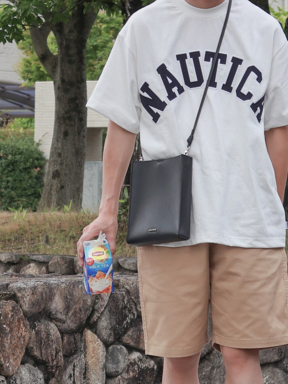 ホワイト系のTシャツ/カットソー、ブラック系のショルダーバッグ、ブルー系のスニーカーを着用したメンズの夏コーディネートの3枚目の写真