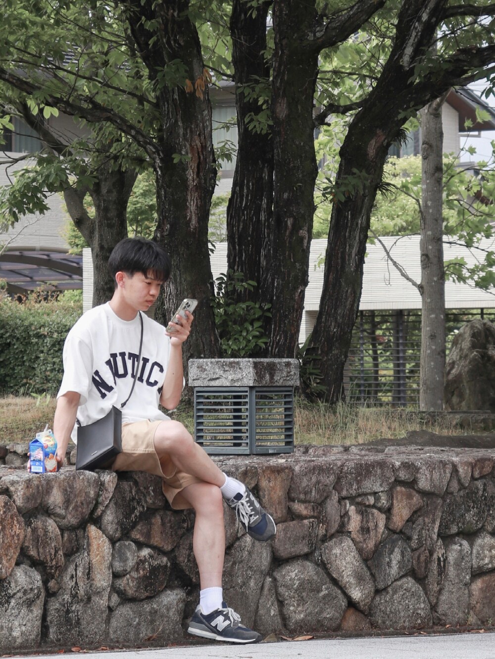 ホワイト系のTシャツ/カットソー、ブラック系のショルダーバッグ、ブルー系のスニーカーを着用したメンズの夏コーディネートの2枚目の写真