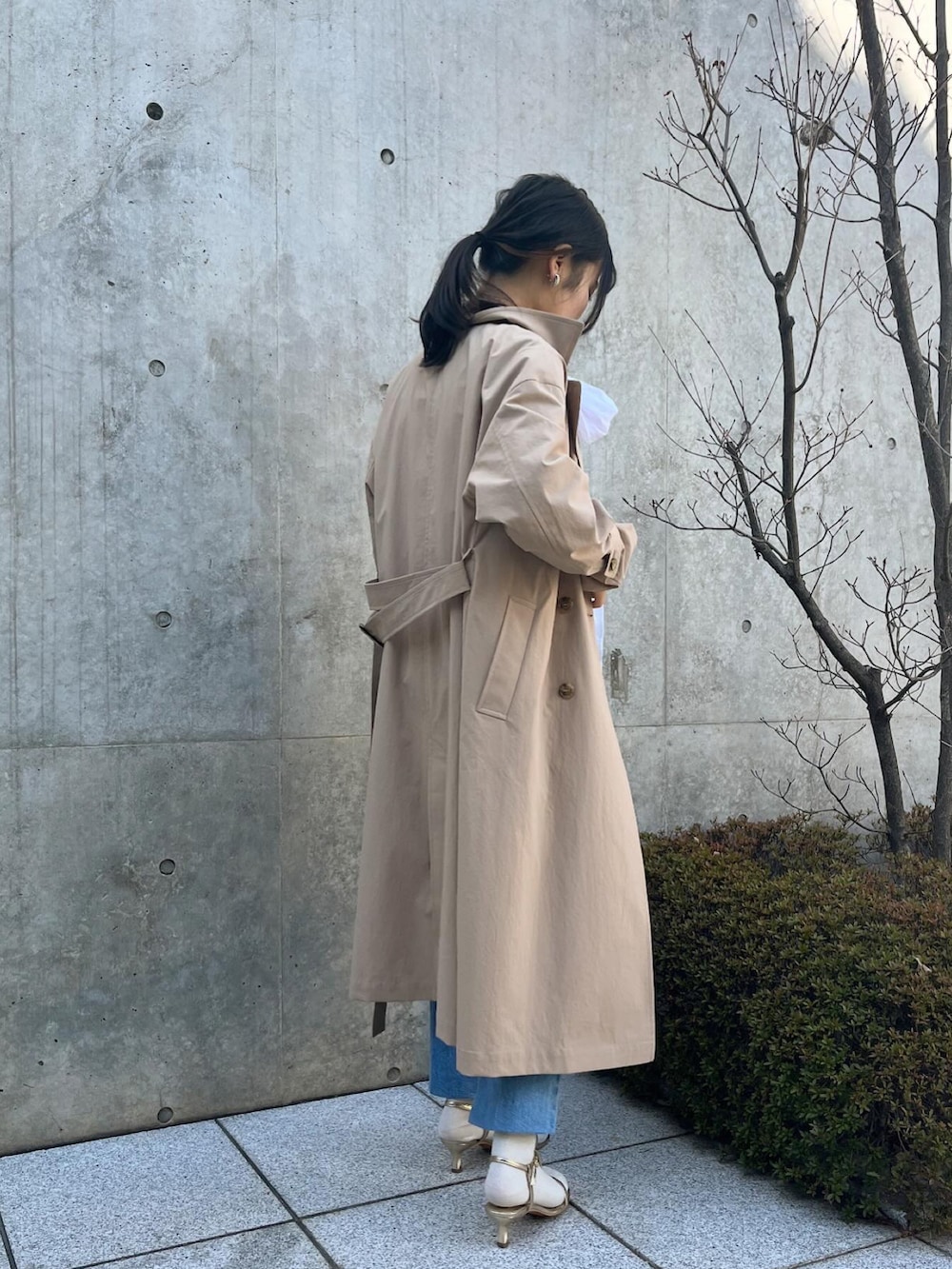 ホワイト系のシャツ/ブラウス、ベージュ系のトレンチコート、ブルー系のデニムパンツを着用したレディースの春コーディネートの5枚目の写真