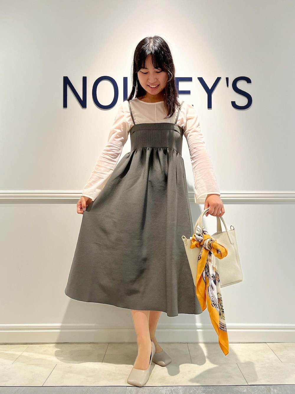 ホワイト系のTシャツ/カットソー、グレー系のスカート、ホワイト系のトートバッグを着用したレディースの秋コーディネートの2枚目の写真